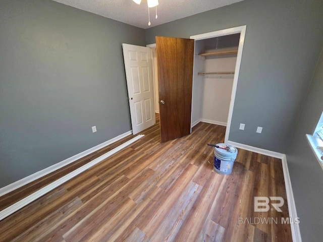 unfurnished bedroom with a closet, baseboards, wood finished floors, and a textured ceiling
