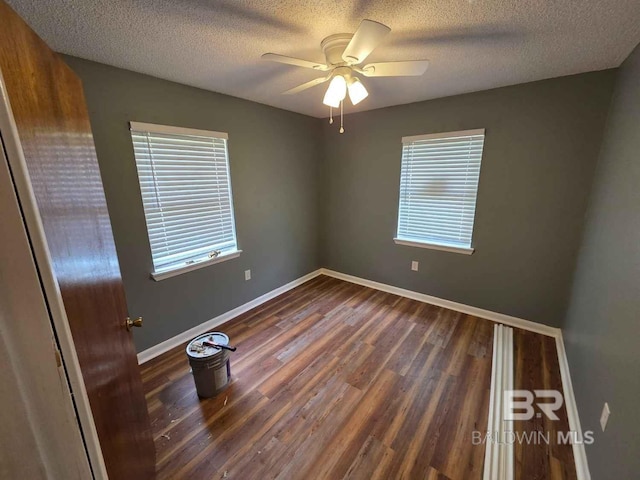 spare room featuring wood finished floors, plenty of natural light, a textured ceiling, baseboards, and ceiling fan
