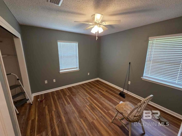 unfurnished bedroom featuring a textured ceiling, wood finished floors, baseboards, a ceiling fan, and a closet