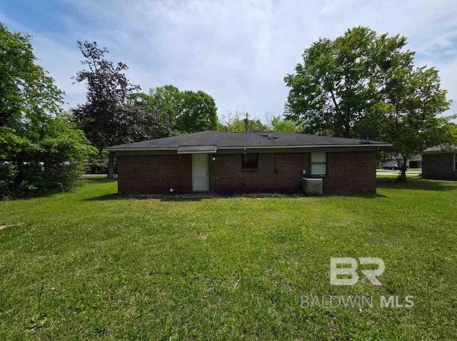 rear view of house with a yard, brick siding, and central air condition unit