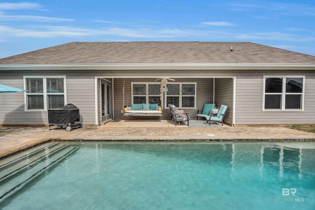 rear view of property featuring ceiling fan, a shingled roof, an outdoor living space, and an outdoor pool