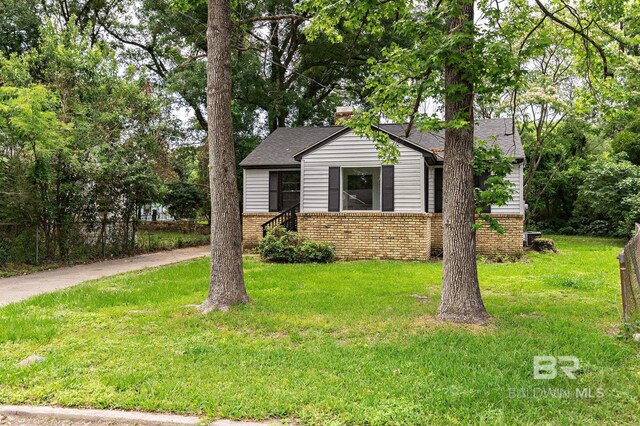 view of front of home with a front lawn, a shingled roof, and brick siding