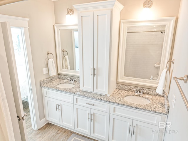 full bath featuring double vanity, a sink, and wood finished floors