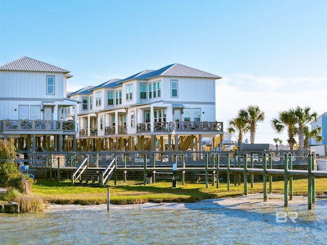 back of house with metal roof, a water view, and a residential view