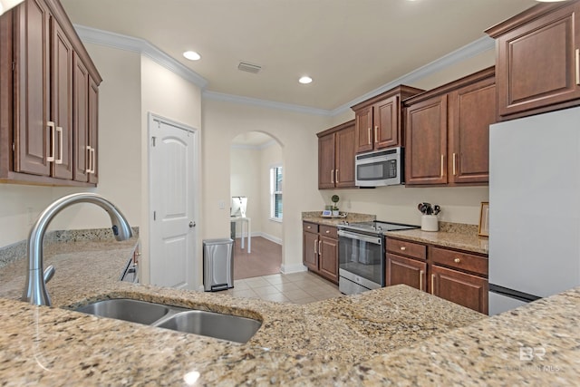 kitchen featuring light stone countertops, crown molding, appliances with stainless steel finishes, and sink