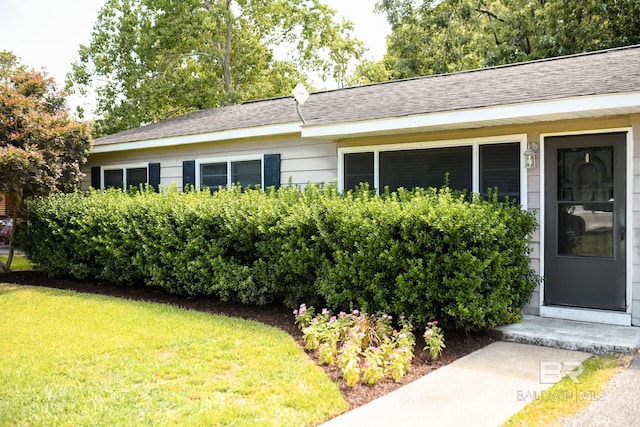 exterior space featuring roof with shingles and a yard