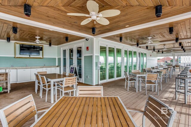 wooden terrace with a water view and ceiling fan