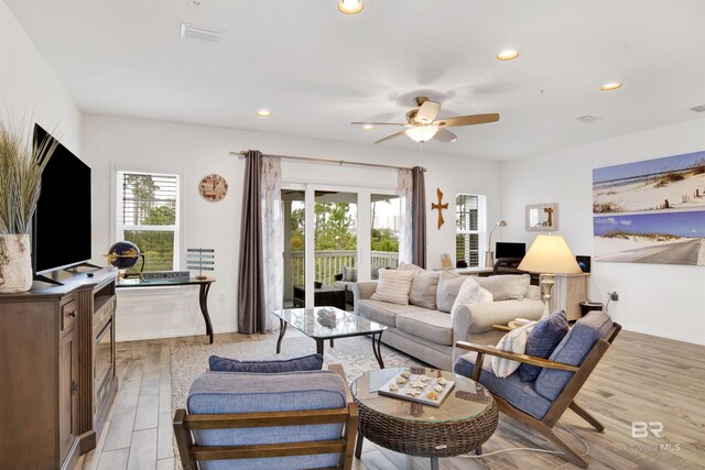 living room featuring light hardwood / wood-style flooring and ceiling fan with notable chandelier