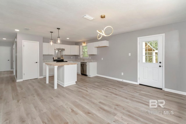 kitchen featuring pendant lighting, stove, light wood-type flooring, white cabinetry, and a kitchen island