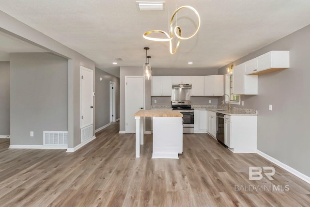 kitchen featuring white cabinets, light wood-type flooring, stainless steel appliances, sink, and a kitchen island