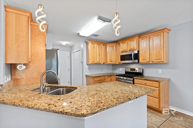 26715 Terry Cove Dr, Orange Beach, AL 36561 - kitchen featuring stainless steel appliances, a sink, a peninsula, light stone counters, and baseboards