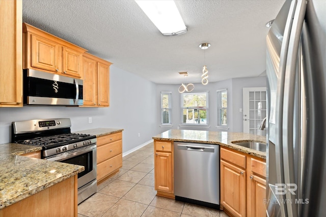 26715 Terry Cove Dr, Orange Beach, AL 36561 - kitchen featuring appliances with stainless steel finishes, a sink, light tile patterned floors, light stone countertops, and a peninsula