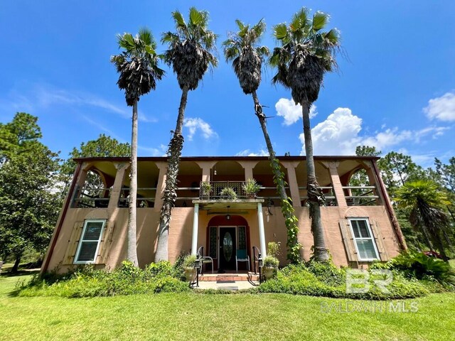 view of front of home with a balcony and a front lawn