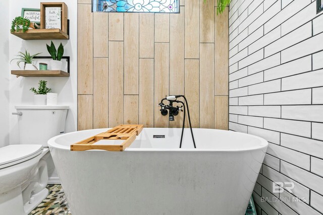 bathroom featuring a tub to relax in, toilet, and wooden walls