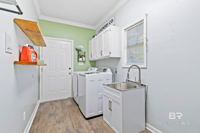 laundry area with cabinets, ornamental molding, sink, light hardwood / wood-style flooring, and washing machine and dryer