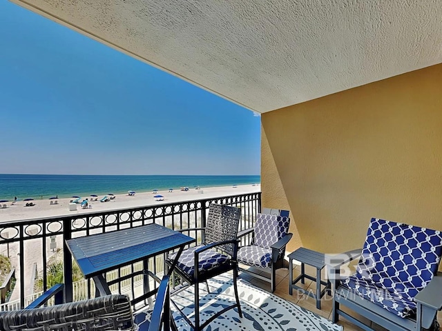 balcony featuring a view of the beach and a water view