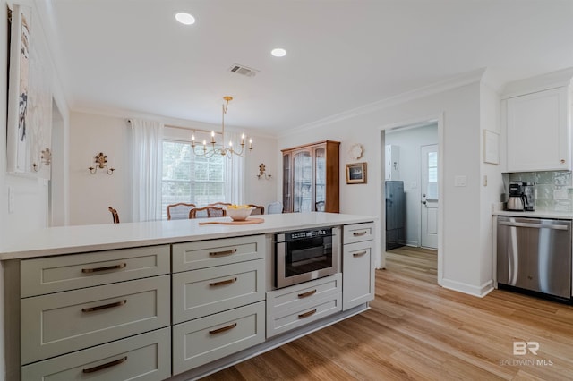 kitchen featuring crown molding, light hardwood / wood-style flooring, hanging light fixtures, tasteful backsplash, and stainless steel dishwasher