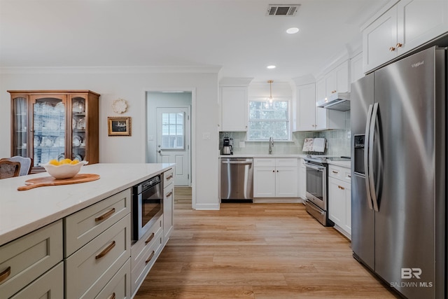 kitchen with pendant lighting, white cabinetry, stainless steel appliances, and backsplash