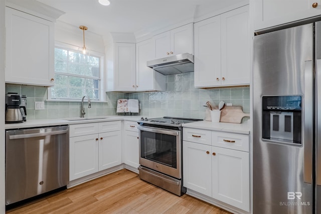 kitchen featuring white cabinetry, sink, hanging light fixtures, light hardwood / wood-style floors, and stainless steel appliances