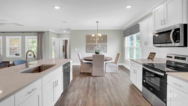 11529 Thistledown Loop, Spanish Fort, AL 36527 - kitchen featuring stainless steel appliances, a sink, light wood finished floors, a chandelier, and baseboards