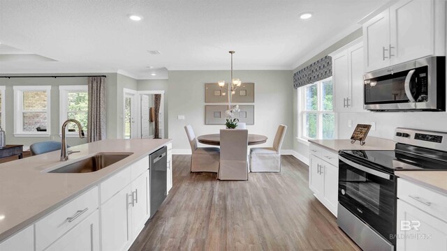 11529 Thistledown Loop, Spanish Fort, AL 36527 - kitchen with stainless steel appliances, a sink, light wood-style flooring, a chandelier, and baseboards