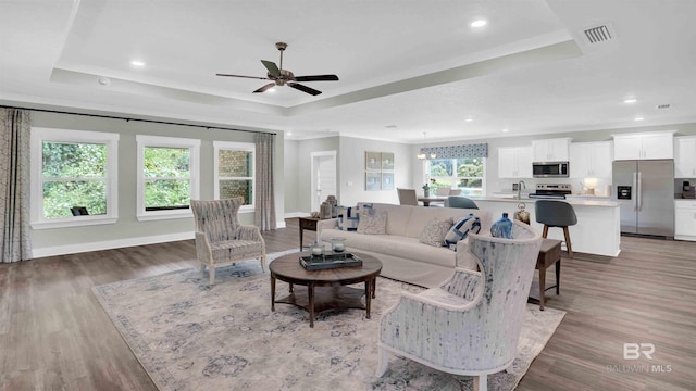 11529 Thistledown Loop, Spanish Fort, AL 36527 - living area featuring a raised ceiling, ornamental molding, a ceiling fan, light wood-style flooring, and baseboards