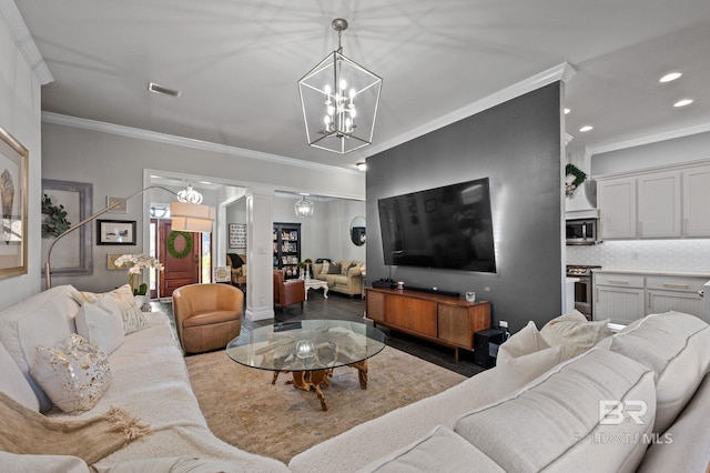 living area featuring ornate columns, visible vents, a chandelier, and crown molding