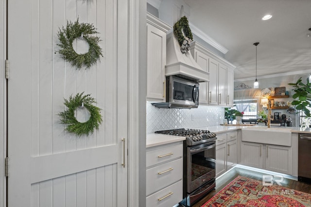 kitchen featuring a sink, light countertops, appliances with stainless steel finishes, backsplash, and crown molding