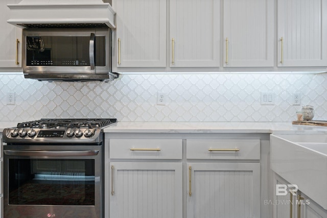 kitchen with appliances with stainless steel finishes, white cabinets, and backsplash