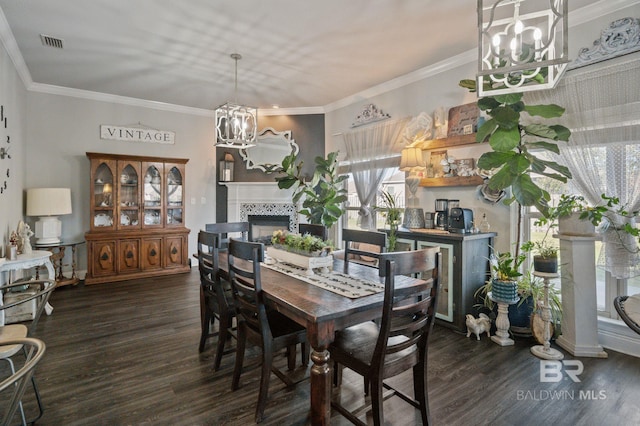 dining space with a tile fireplace, wood finished floors, visible vents, ornamental molding, and an inviting chandelier