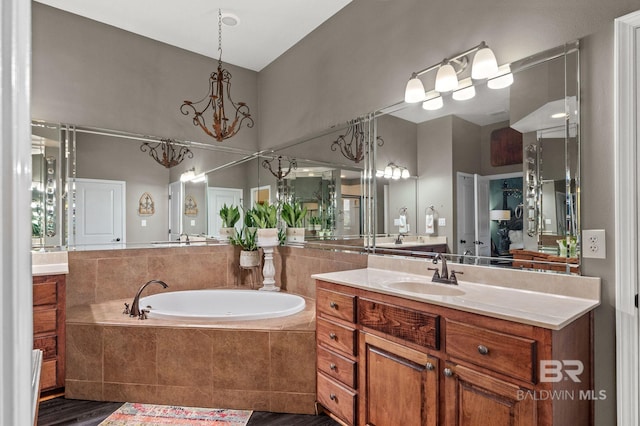 bathroom featuring a garden tub, vanity, and a notable chandelier