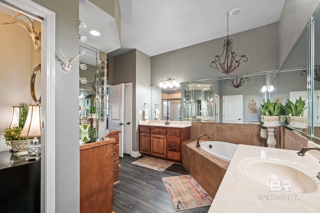 bathroom with two vanities, a sink, a bath, and wood finished floors