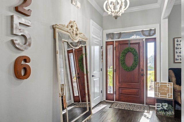 foyer entrance with a notable chandelier, wood finished floors, and crown molding