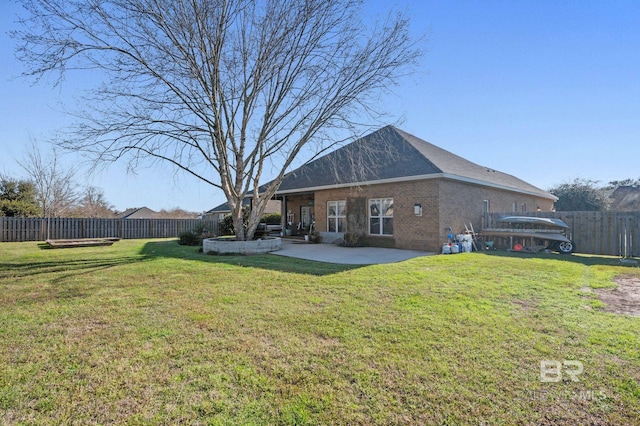 rear view of property with brick siding, a patio, a fenced backyard, and a lawn