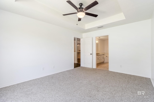 empty room featuring light colored carpet, ceiling fan, and a raised ceiling