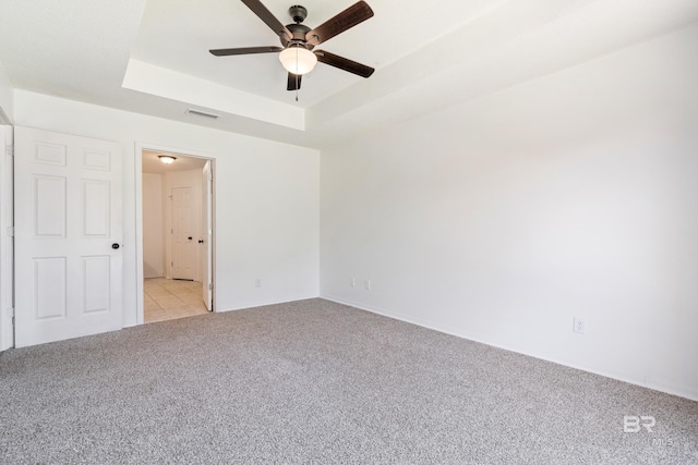 carpeted empty room with a tray ceiling and ceiling fan