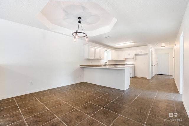 kitchen featuring dark tile floors, kitchen peninsula, hanging light fixtures, a tray ceiling, and white cabinets