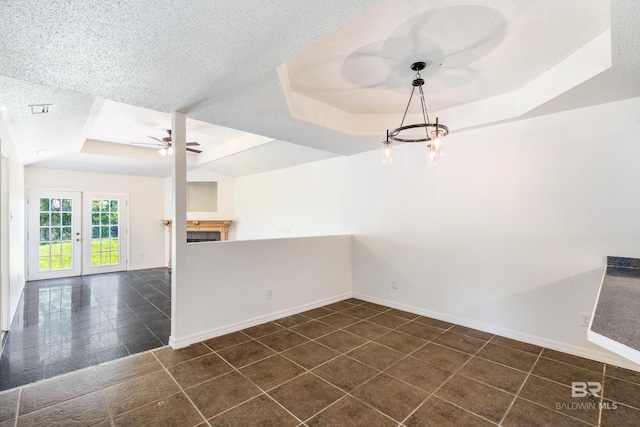 tiled spare room featuring ceiling fan, a tray ceiling, a textured ceiling, and french doors