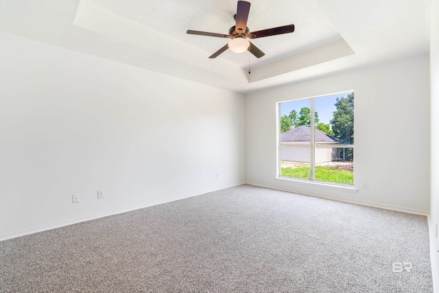 carpeted empty room featuring ceiling fan and a tray ceiling