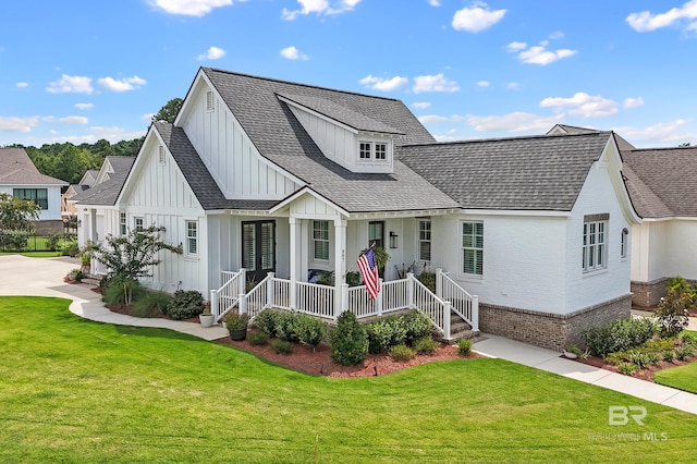 modern inspired farmhouse featuring a front lawn, a porch, board and batten siding, roof with shingles, and brick siding