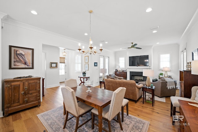 dining room featuring light wood-type flooring, ceiling fan with notable chandelier, and ornamental molding