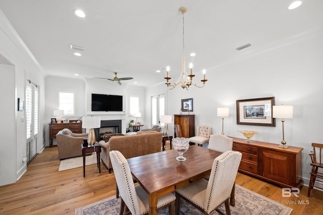 dining area featuring light hardwood / wood-style flooring, ceiling fan with notable chandelier, and crown molding