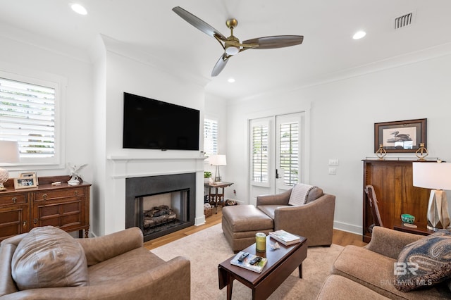 living room with ornamental molding, light hardwood / wood-style flooring, and ceiling fan