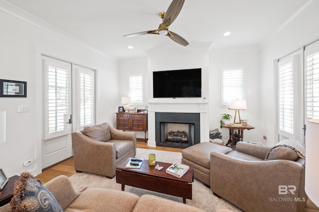 living room with light hardwood / wood-style floors, ceiling fan, and crown molding