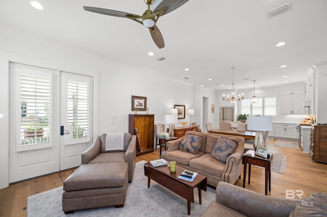 living room featuring light hardwood / wood-style floors, ceiling fan with notable chandelier, and crown molding