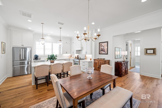 dining room with a chandelier, light wood-type flooring, and ornamental molding