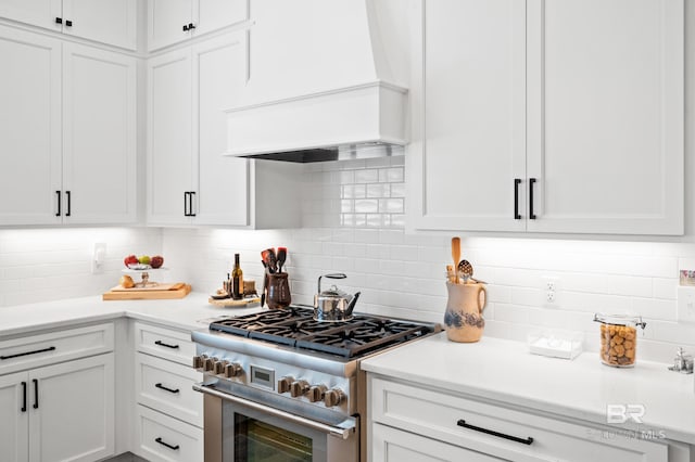 kitchen with white cabinetry, premium range hood, tasteful backsplash, and high end stainless steel range