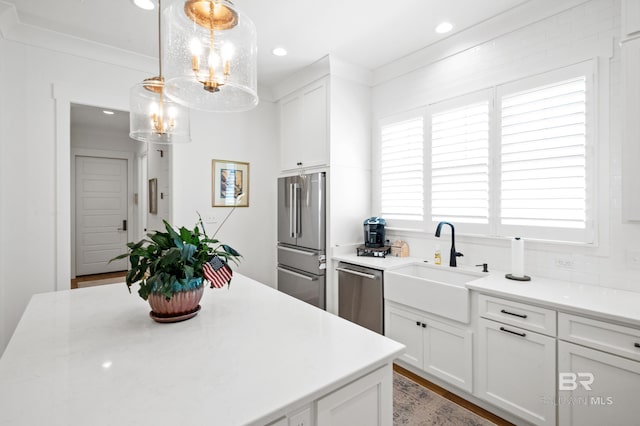 kitchen featuring appliances with stainless steel finishes, white cabinets, a wealth of natural light, and pendant lighting