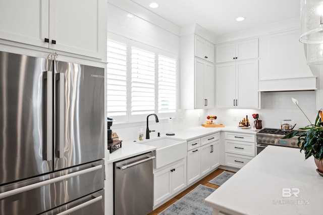 kitchen featuring a sink, light countertops, white cabinetry, high quality appliances, and backsplash