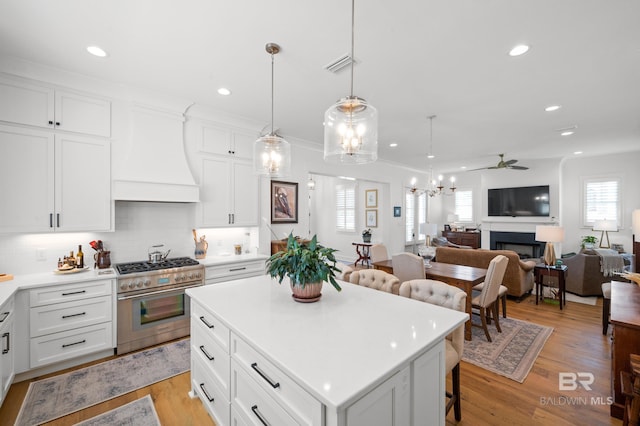 kitchen featuring custom range hood, high end stainless steel range oven, light hardwood / wood-style floors, and a kitchen island